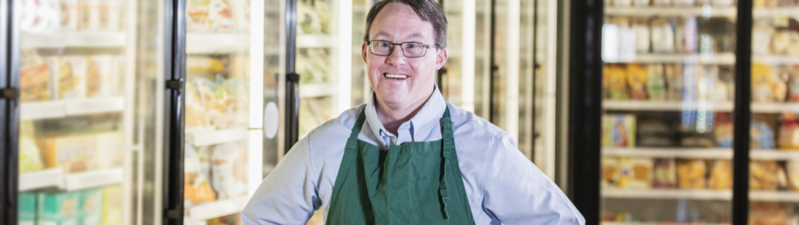 young man with Down syndrome smiling at work in a grocery store